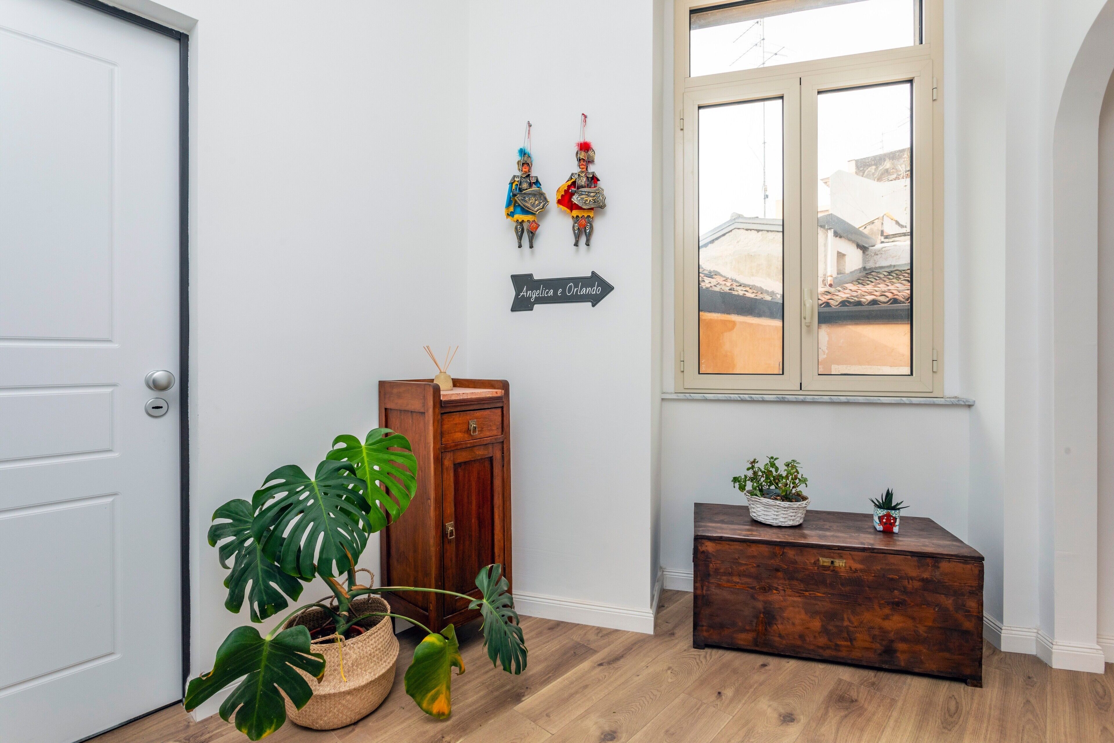 Um corredor com um armário de madeira, uma planta em vaso e um ornamento na parede.