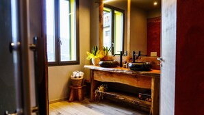 Un baño con tocador de madera, un lavabo y un espejo.