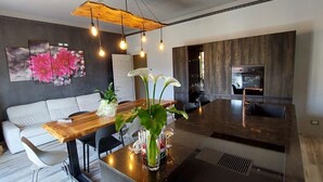 Una cocina moderna con una isla de madera, un rincón comedor con sofá blanco y una gran obra de arte floral en la pared.