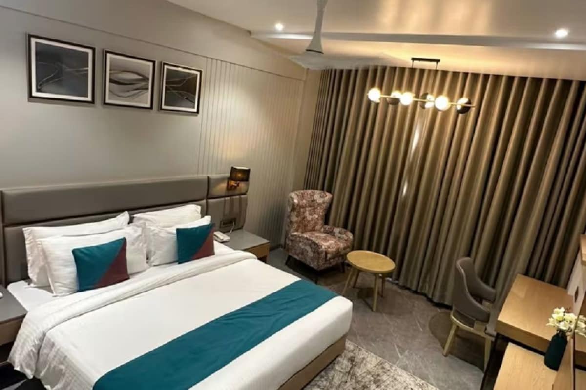 A hotel room with a bed, a chair, a desk, and a curtain.