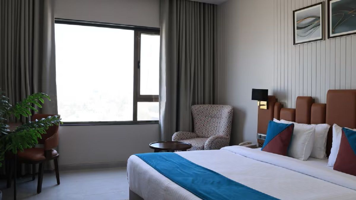 Ein Hotelzimmer mit einem großen Bett, einem Sessel, einem kleinen Tisch und einer Zimmerpflanze.