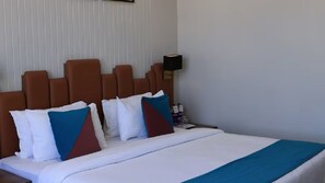 A hotel room with a bed, pillows, a nightstand, and a lamp. - Pride Elite Dwarka (Dwarka)