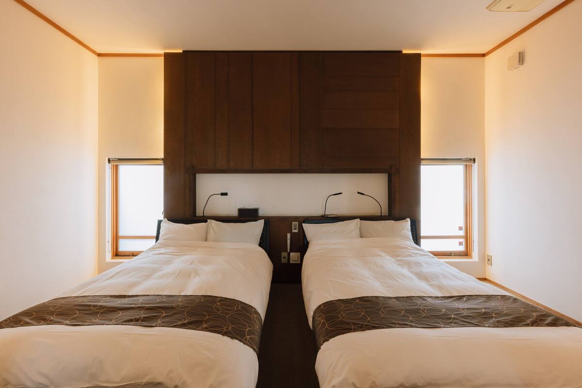 A double bed with a headboard, two bedside tables, and a window on each side.