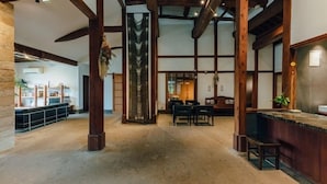 A spacious interior with high ceilings, exposed wooden beams, a central column, and a reception area with a counter and seating. - Fukahoritei (Kurume)