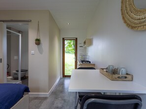 Ein modernes Zimmer mit Bett, Esstisch, Küchenzeile und Bad.