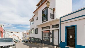 Un edificio de dos plantas con un letrero que dice '3 Marinas' en la planta baja, fachada blanca y una puerta azul a la derecha.