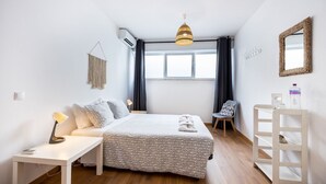 Un dormitorio con cama, mesita de noche, silla, escritorio y espejo.