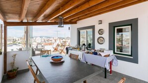 Comedor con una mesa para cuatro, vigas de madera en el techo y vistas a la ciudad a través de amplias ventanas.