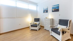 Una habitación con dos sillones, un aparador y dos cuadros en la pared.