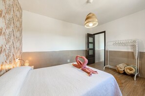 A hotel room with a bed, a hanging light fixture, a towel rack with towels, and a door. - Holiday Home 'Nido' with Private Terrace and Air Conditioning (Nijar)