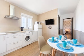 A modern kitchen with a microwave, washing machine, and a TV mounted on the wall.