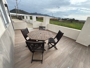 A patio with a wooden table and chairs, a view of a green field, and a mountain in the background. - Holiday Home 'Nido' with Private Terrace and Air Conditioning (Nijar)