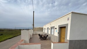 A building with a patio area, a table with chairs, and a door.