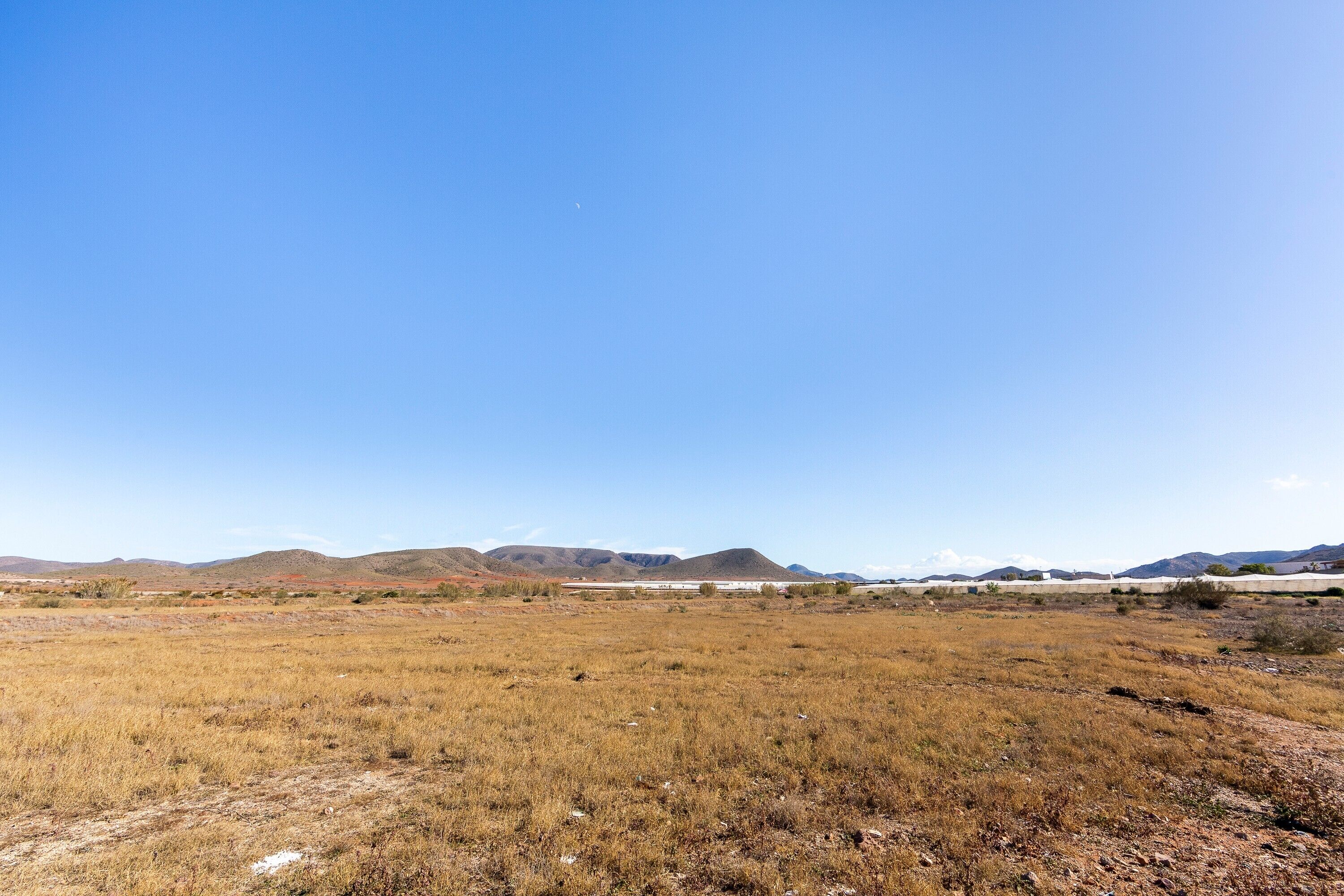 Un paisaje llano y abierto, con montañas lejanas y cielo despejado.