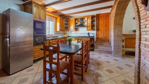 A kitchen with wooden cabinets, a central island with chairs, a refrigerator, and a microwave. - Holiday Home 'La Tierra' with Private Terrace (Nijar)