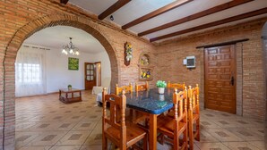 A dining area with a brick wall, wooden chairs, a table, and a chandelier. - Holiday Home 'La Tierra' with Private Terrace (Nijar)