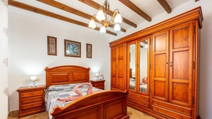 A bedroom with a wooden bed, nightstands, a wardrobe, and a chandelier. - Holiday Home 'La Tierra' with Private Terrace (Nijar)