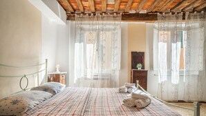 Ein Schlafzimmer mit einem Bett, einem Nachttisch, einer Kommode und transparenten Vorhängen.