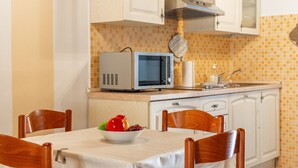 Eine kleine Küche mit Mikrowelle, Spüle und einem Tisch mit Stühlen.