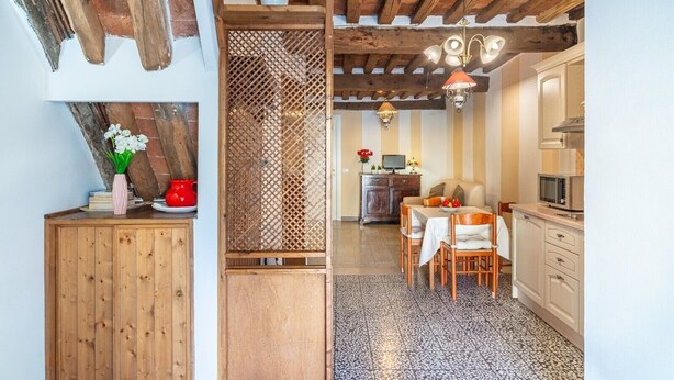 Eine Küche mit Holzausstattung, ein Essbereich mit Tisch und Stühlen sowie eine Decke mit freiliegenden Balken.