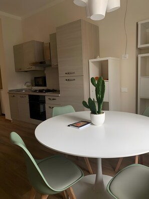 A modern kitchen with white cabinets, a stove, and a dining table with chairs.
