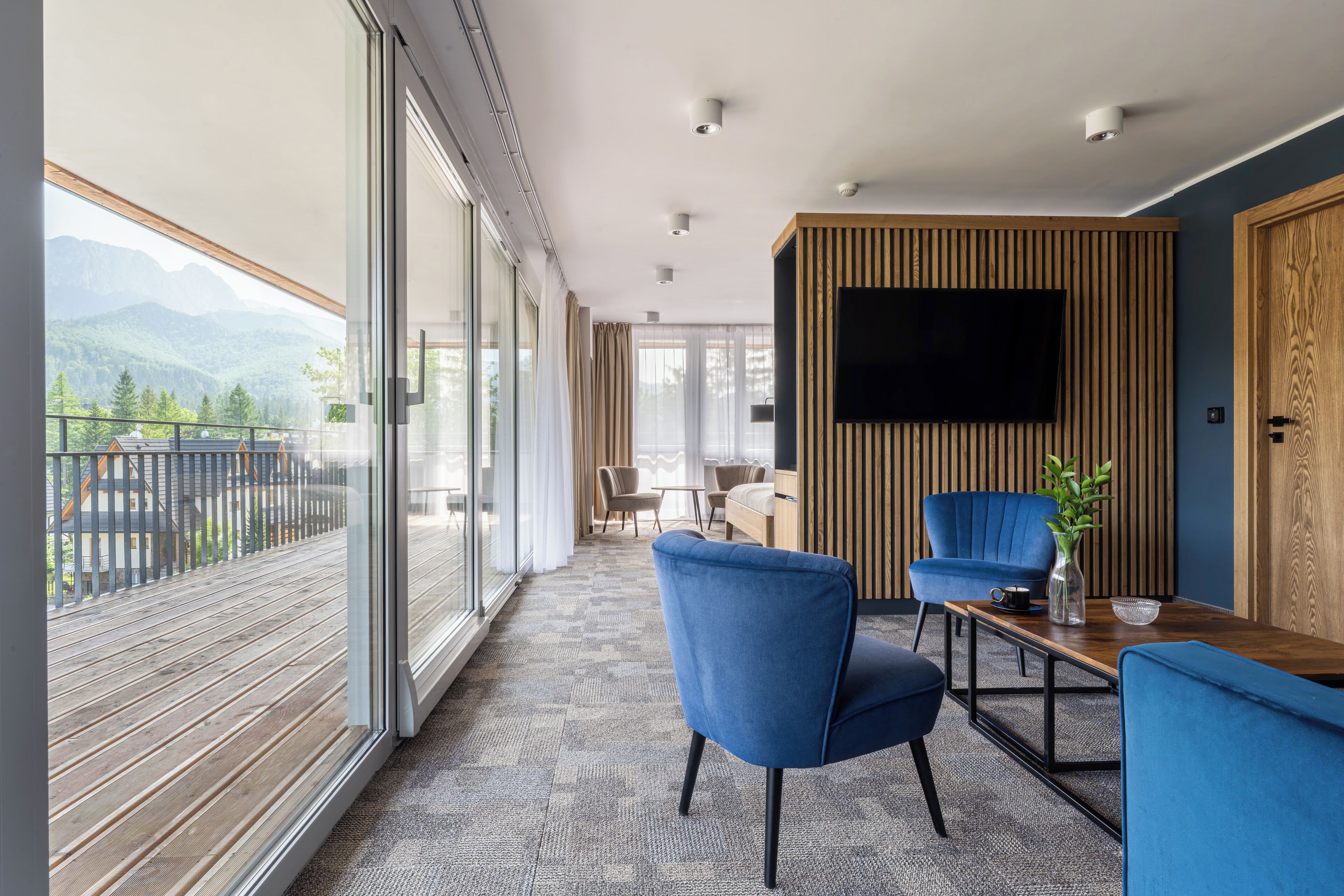 Una habitación moderna con un amplio ventanal, un televisor de pantalla plana y techo de madera.