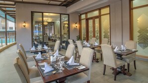 Un espace repas avec plusieurs tables dressées pour accueillir les clients, présentant un design moderne avec des tables en bois et des chaises rembourrées.
