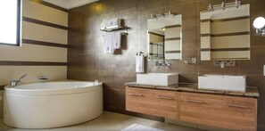 Un baño moderno con una bañera independiente, dos lavamanos y espejos grandes.