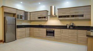 Una cocina moderna con un refrigerador de acero inoxidable, horno empotrado y muebles de madera.
