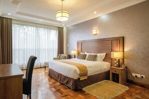 Una habitación de hotel con una cama grande, lámparas de noche, un escritorio y una silla.