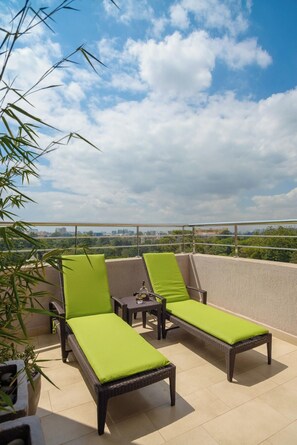 Terraza en la azotea con dos sillones de mimbre y una mesita, con vistas a un paisaje urbano.