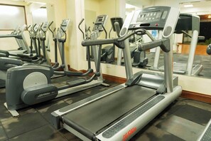 Un gimnasio con varias cintas de correr y elípticas.
