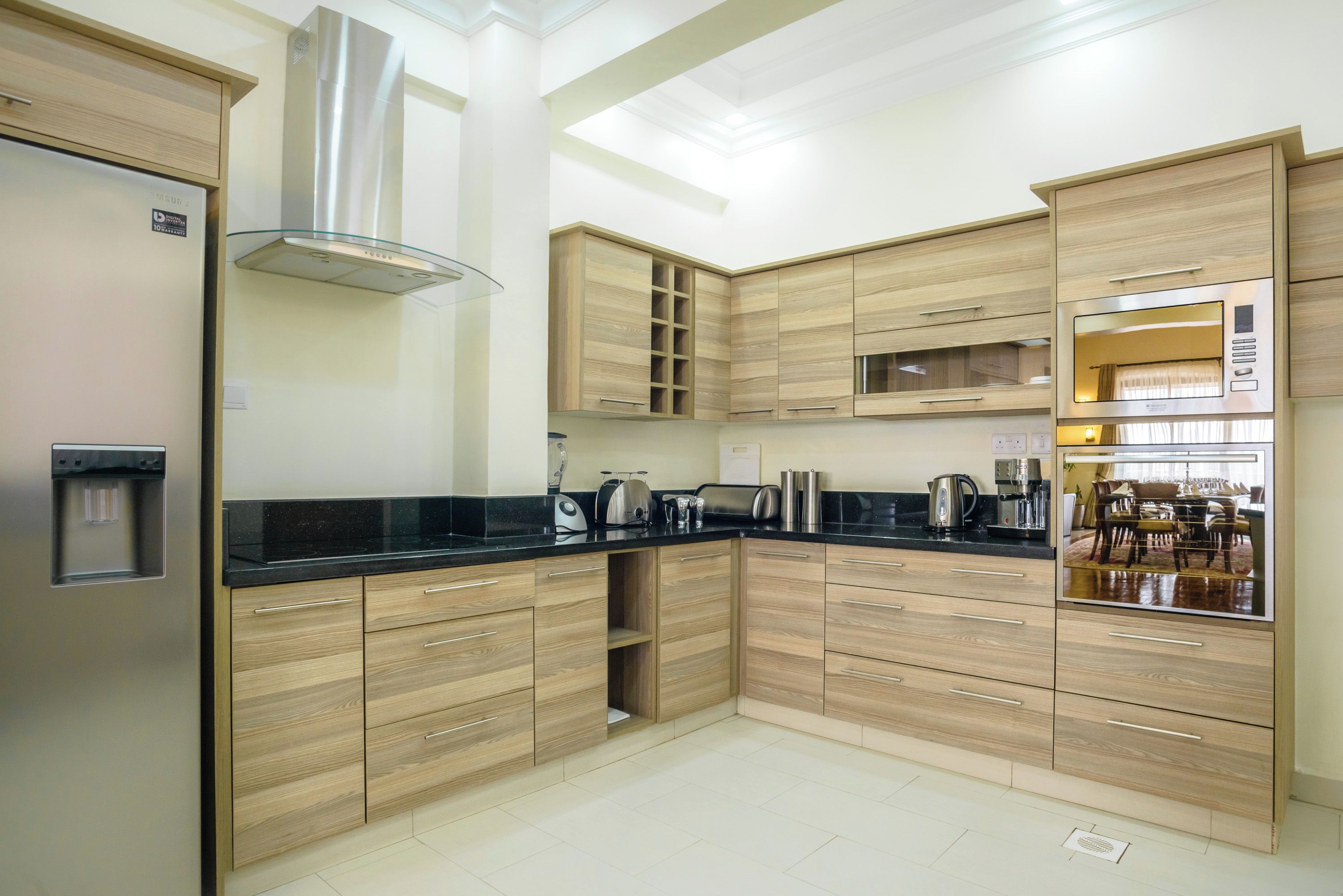 Uma cozinha moderna com armários de madeira, bancada preta e eletrodomésticos de aço inoxidável.