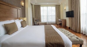 Una habitación de hotel con una cama grande, un escritorio, una silla y un televisor.