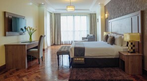 A hotel room with a bed, desk, chair, and a TV on the wall. - Gem Suites Hotel & Luxury Serviced Apartments (Nairobi)