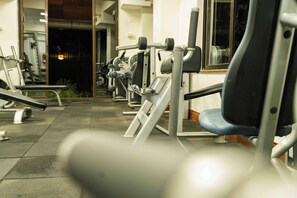 Un gimnasio con equipo de ejercicio, una banca y una silla.