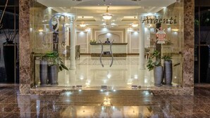 Un hall d’hôtel avec un comptoir d’accueil, des plantes en pot et un lustre.