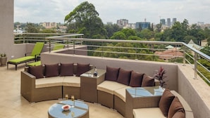 Une terrasse sur le toit aménagée avec un canapé incurvé, une table ronde et un fauteuil de relaxation.