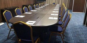 A conference room with a long table and chairs, a projector screen, and a carpeted floor. - Gem Suites Hotel & Luxury Serviced Apartments (Nairobi)
