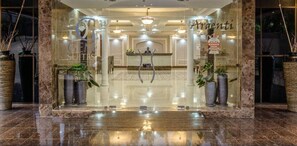 A hotel lobby with a reception desk, potted plants, and a chandelier. - Gem Suites Hotel & Luxury Serviced Apartments (Nairobi)