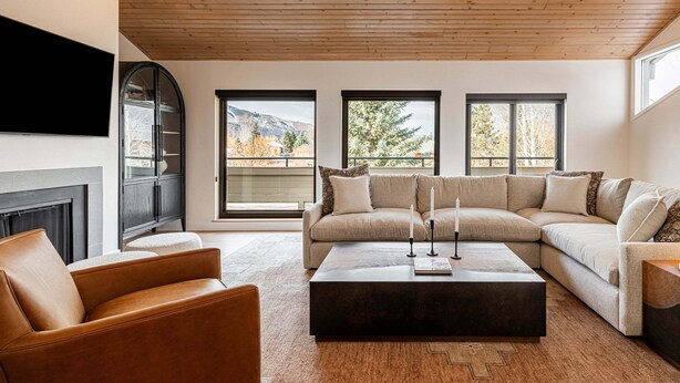 A living room with a sectional sofa, a coffee table, a fireplace, and large windows with a view of mountains. - Newly furnished with private hot tub in Prospector community (Park City)