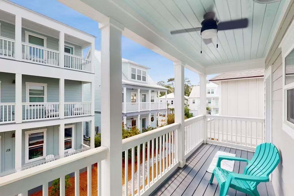 A multi-story building with a balcony, a ceiling fan, and a turquoise chair.