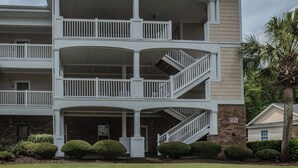 A multi-story building with balconies, a covered entryway, and a brick facade.