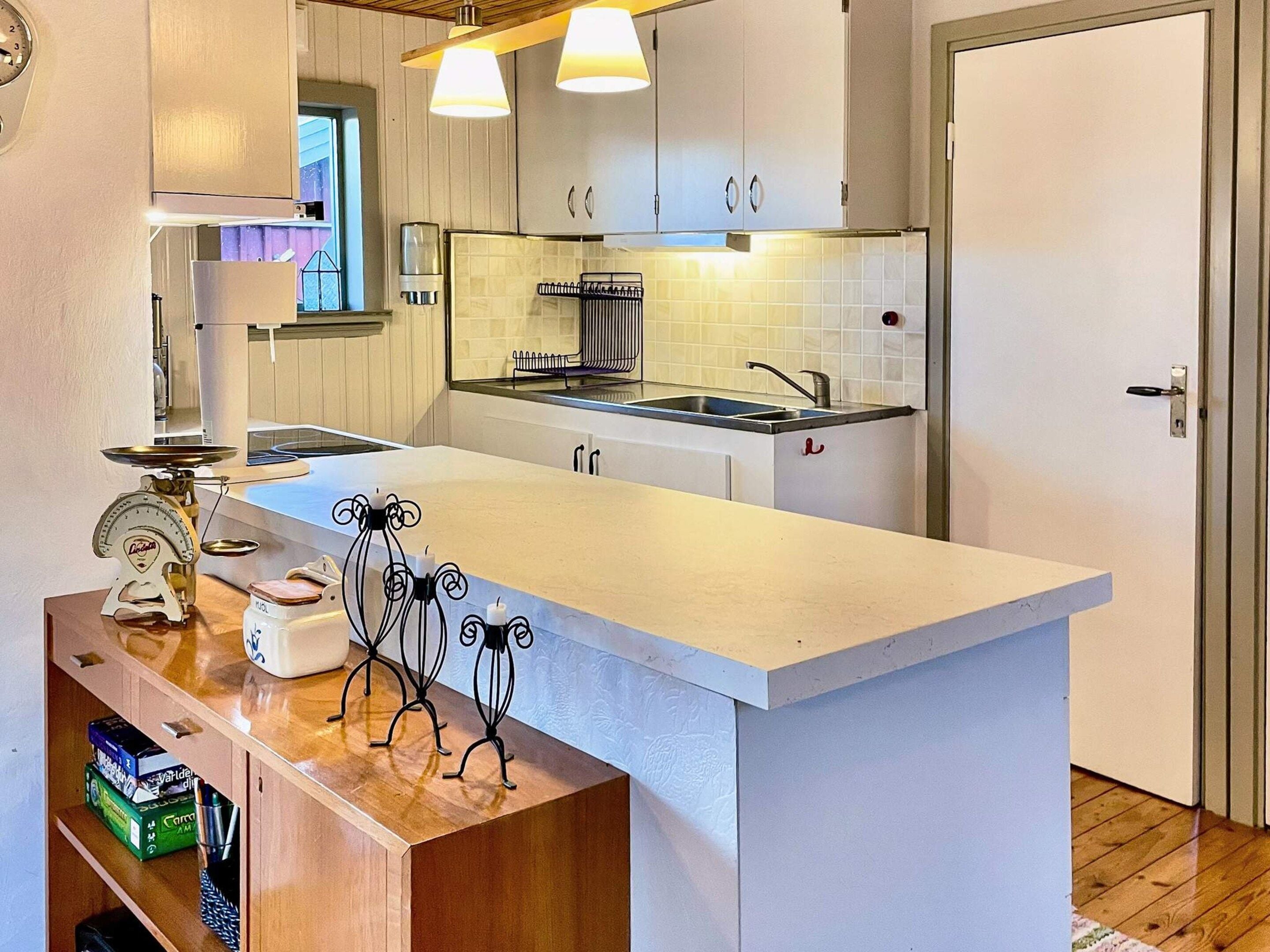 A kitchen with a central island, white cabinets, a stainless steel sink, and a window above the sink.