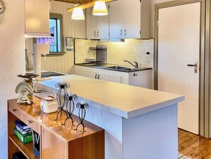 A kitchen with a central island, white cabinets, a stainless steel sink, and a window above the sink. - 4 Person Holiday Home in Farjestaden (Farjestaden)