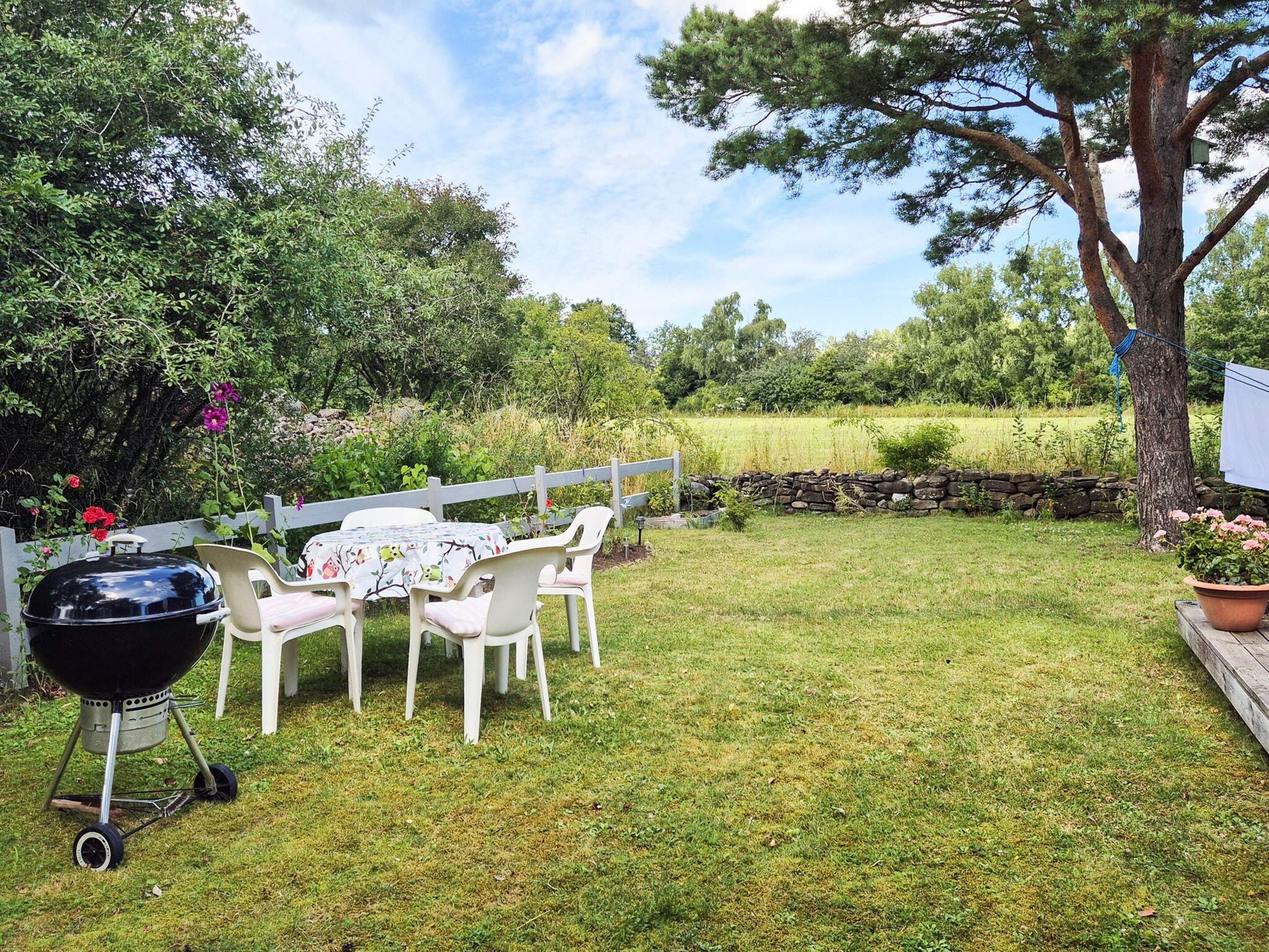 A backyard with a barbecue grill, a table with chairs, and a wooden fence.