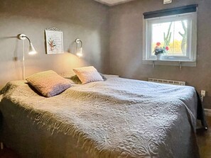 A bedroom with a bed, bedside lamps, a window with a view, and a wall-mounted picture. - 4 Person Holiday Home in Farjestaden (Farjestaden)
