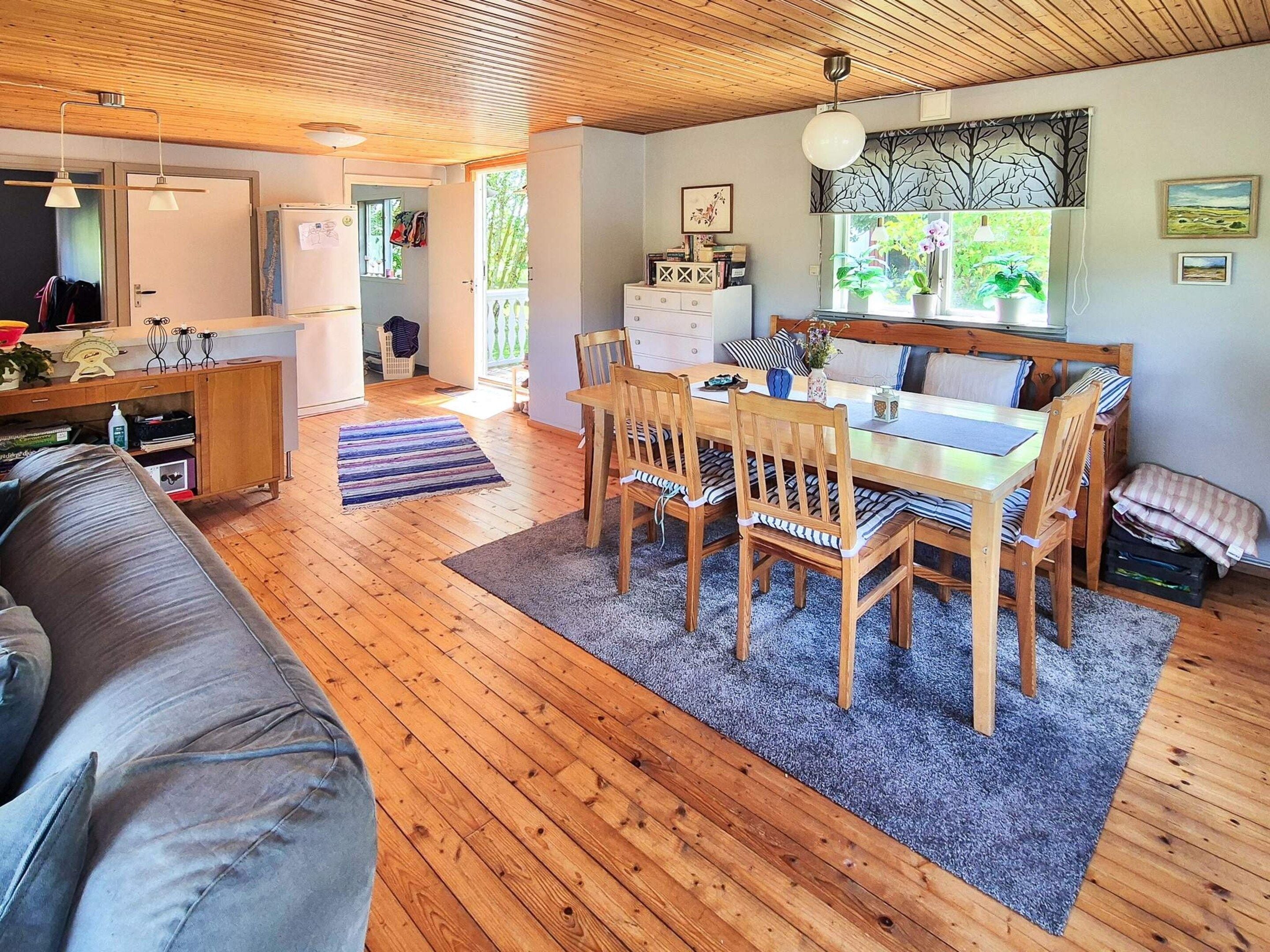 Un interior acogedor con una mesa de comedor de madera, sillas, un sofá y una zona de cocina.