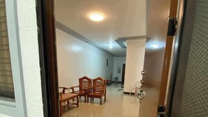 Un pasillo con una zona de comedor que incluye sillas de madera y una mesa, una puerta con manija de metal y piso de baldosas.