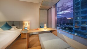 A modern hotel room with a bed, bedside table, lamp, and a view of the cityscape. - Pagoda Hotel Hangzhou Zijingang - Near Zhejiang University and Xixi National Wetland Area (Hangzhou)